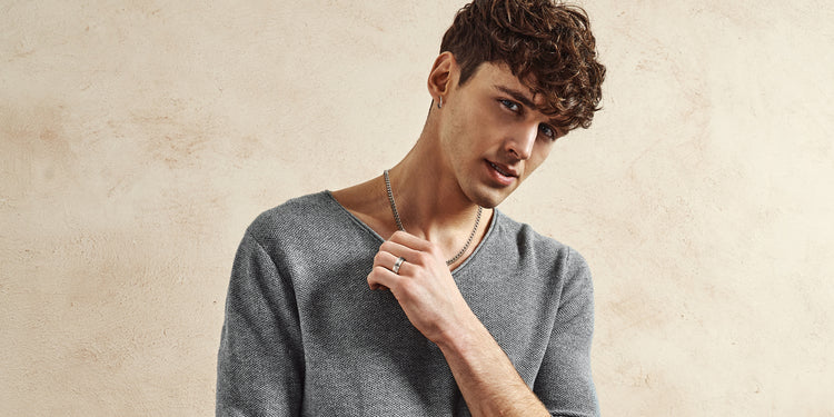 Junger Mann mit lockigen Haaren trägt silberne Panzerkette und silbernen Ring