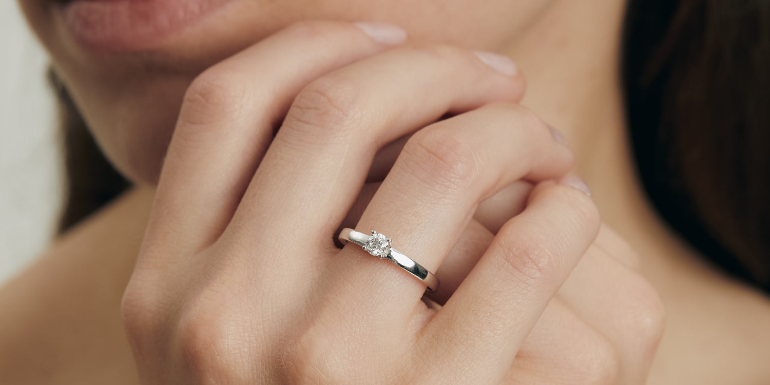 Verlobungsring in Weißgold mit Diamant-Solitär an Damenhand, eleganter Verlobungsschmuck